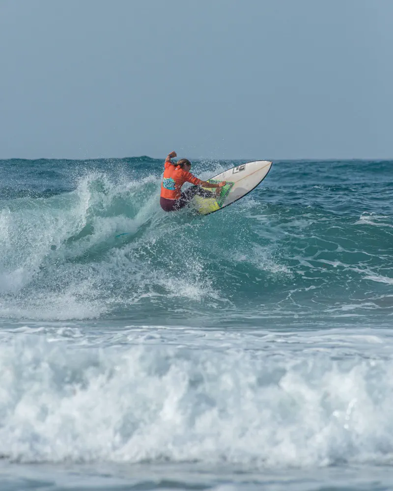 A surfer in a Buen Surf jersey turning off the lip, spray thrown behind the board